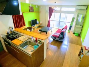 a kitchen with a sink and a living room with green walls at ゲストハウス ルルル 最大12名可 合宿 大家族 団体旅行にオススメ in Kochi
