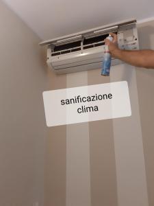 une personne tenant une bouteille de désodorisant sur la climatisation dans l'établissement Sweet House Only Rooms, à Peschiera del Garda