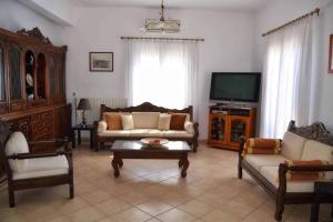 een woonkamer met een bank en een tv bij Aegina House in Aegina Town