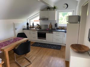 a kitchen with white cabinets and a table with chairs at 5-Sterne Active Ferienwohnung Chiemgau in Marquartstein