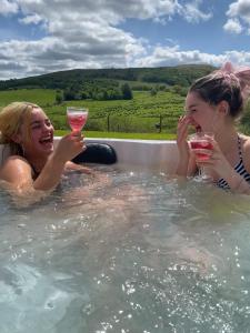two women in a hot tub with glasses of wine at Healing Pastures Farm in Llanbrynmair