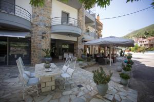 patio con tavolo, sedie e ombrellone di Delfini Hotel a Menídion