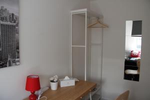 a room with a desk with a red lamp and a shelf at Kamilla's Rooms London Zone-1 in London