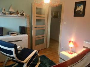 uma sala de estar com uma cadeira, uma mesa e um candeeiro em Apartament Środziemnomorski em Jastrzebia Gora