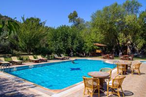 a swimming pool with tables and chairs and a table and chairs at Doga Apartments in Kayakoy