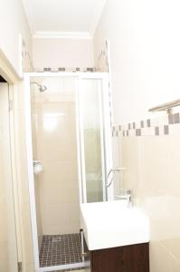 y baño con ducha y lavabo blanco. en Lily's Haven en Durban