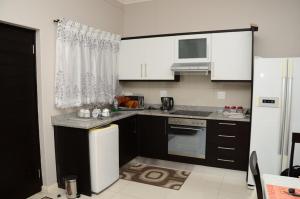 a kitchen with black cabinets and a white refrigerator at Lily's Haven in Durban