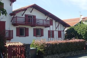 西布勒的住宿－Chambres d'hôtes Gela Itsasoa Océan，白色的房子,设有红色的阳台和围栏