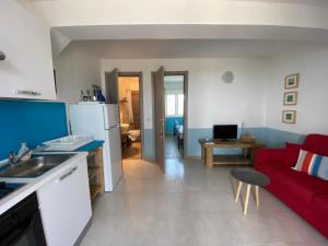 een keuken en een woonkamer met een rode bank bij Casa Cologna Appartementen in Roseto degli Abruzzi