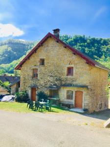 a stone house with benches and a table in front of it at Gîte des reculées in Ladoye-sur-Seille