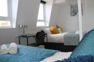 a bedroom with two beds and a desk and two windows at Kamilla's Rooms London Zone-1 in London