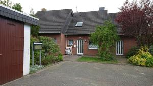 une maison en briques rouges avec un garage et une allée. dans l'établissement Ferienhaus Möwe, à Butjadingen