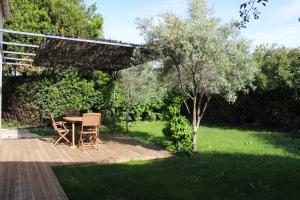 un patio con mesa y sillas en un jardín en Les Airis, en Aviñón