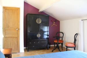 a bedroom with a black cabinet and two chairs at Les Airis, maison de vacances écologique in Avignon +17 photos