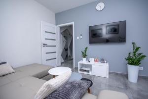 a white living room with a couch and a tv at Apartamenty AP 11 in Częstochowa