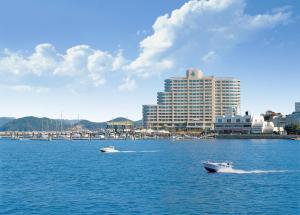 dwie łodzie w wodzie przed dużym budynkiem w obiekcie Kumho Tongyeong Marina Resort w mieście Tongyeong