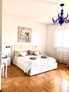 a bedroom with a large white bed with a chandelier at B&B la Serenissima in Fossalta di Portogruaro