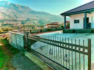 a fence in front of a house with mountains in the background at Eco lodge apartment in Bar