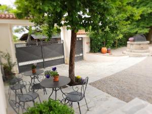 a group of tables and chairs under a tree at Dvor Vipolže in Dobrovo