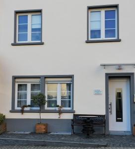 um banco em frente a um edifício branco com janelas em Ferienwohnungen Stadtgeflüster em Cochem