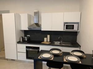 a kitchen with white cabinets and a table with plates on it at Luxury Valletta Apartment in Valletta