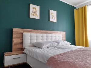 a bedroom with a bed and a blue wall at Emerald Apartament in Białystok