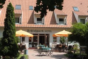 un ristorante con tavoli e ombrelloni di fronte a un edificio di Schlossparkhotel Sallgast a Sallgast
