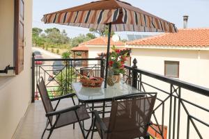 una mesa y sillas en un balcón con sombrilla en Chrissomallis Apartments en Skiathos