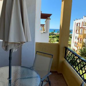 a table and a chair and an umbrella on a balcony at Apartamento Zahara in Zahara de los Atunes