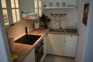 uma pequena cozinha com armários brancos e um lavatório em Ferienwohnung Küstenkind em Wendtorf