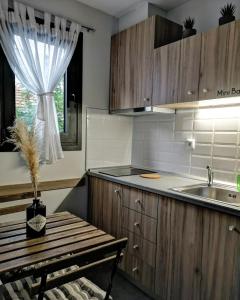 cocina con armarios de madera, fregadero y mesa en Elements Studios en Néa Péramos