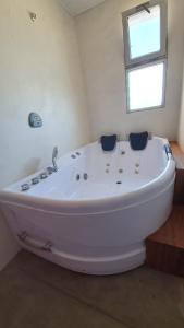 baño con bañera blanca y ventana en Ammunaini en Punta Del Diablo