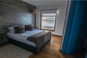 a bedroom with a bed and a large window at Kau Lodge in Puerto Natales