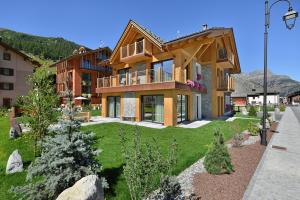 a large house with a green yard in front of it at Roberta Loft - rooms and apartments in Livigno