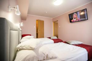 two beds in a hotel room with a tv on the wall at Hotel Unibus in Bielsk Podlaski