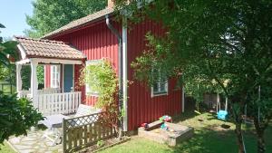 a red house with a porch and a gazebo at RÖDA STUGAN PÅ SLINKEN in Sala