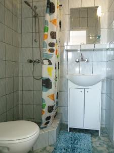 a bathroom with a sink and a toilet and a mirror at Pokoje Gościnne - U Wiktorii in Krynica Morska