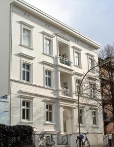 a white building with a balcony on a street at FirstClass Apartments in Hamburg