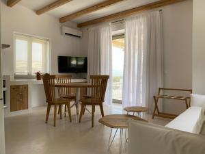 a living room with a table and chairs and a television at LAINI LUXURY SUITES in Pómbia