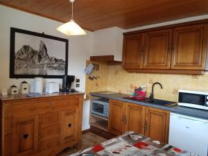 a kitchen with wooden cabinets and a sink and a microwave at Les Saisies coté Légette appartement dans chalet LE NEPAL in Les Saisies