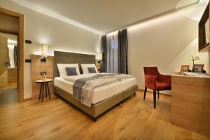 a bedroom with a large bed and a red chair at Roberta Loft - rooms and apartments in Livigno +84 photos