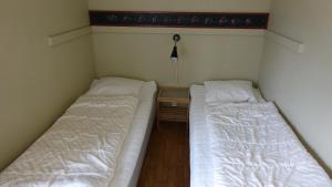 two beds are in a small room with a table at Ekesberget Stugby stuga 6 in Ekshärad