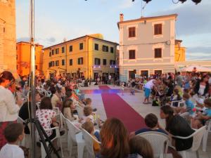 a crowd of people sitting in chairs in front of a stage at Haus Milan AP 1 in Fažana