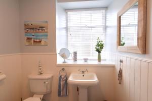 a bathroom with a toilet and a sink and a window at Providence Cottage in Kirkcudbright