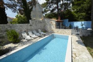 una piscina con sillas y una pared en Villa Avantgarde, en Mlini