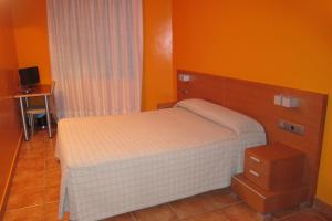 een kleine slaapkamer met een bed en oranje muren bij Ca l'Àngel in Pinell de Bray