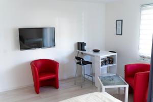 a living room with two red chairs and a tv at Ferienwohnung Dennis in Lörrach