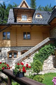 a wooden house with flowers in front of it at Rezydencja Sąsiadów Zakopanego in Zakopane