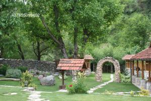 um jardim com uma parede de pedra e um gazebo em ECO GARDEN em Dilijan