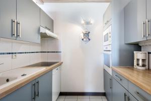ラ・フロットにあるMaison Latitudeのキッチン(白いキャビネット、木製カウンタートップ付)